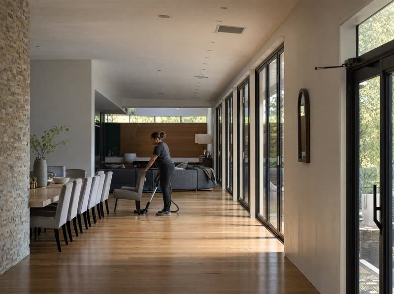 A cleaner working along a sunlit open-plan dining room